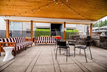 a covered patio with chairs and tables and a grill